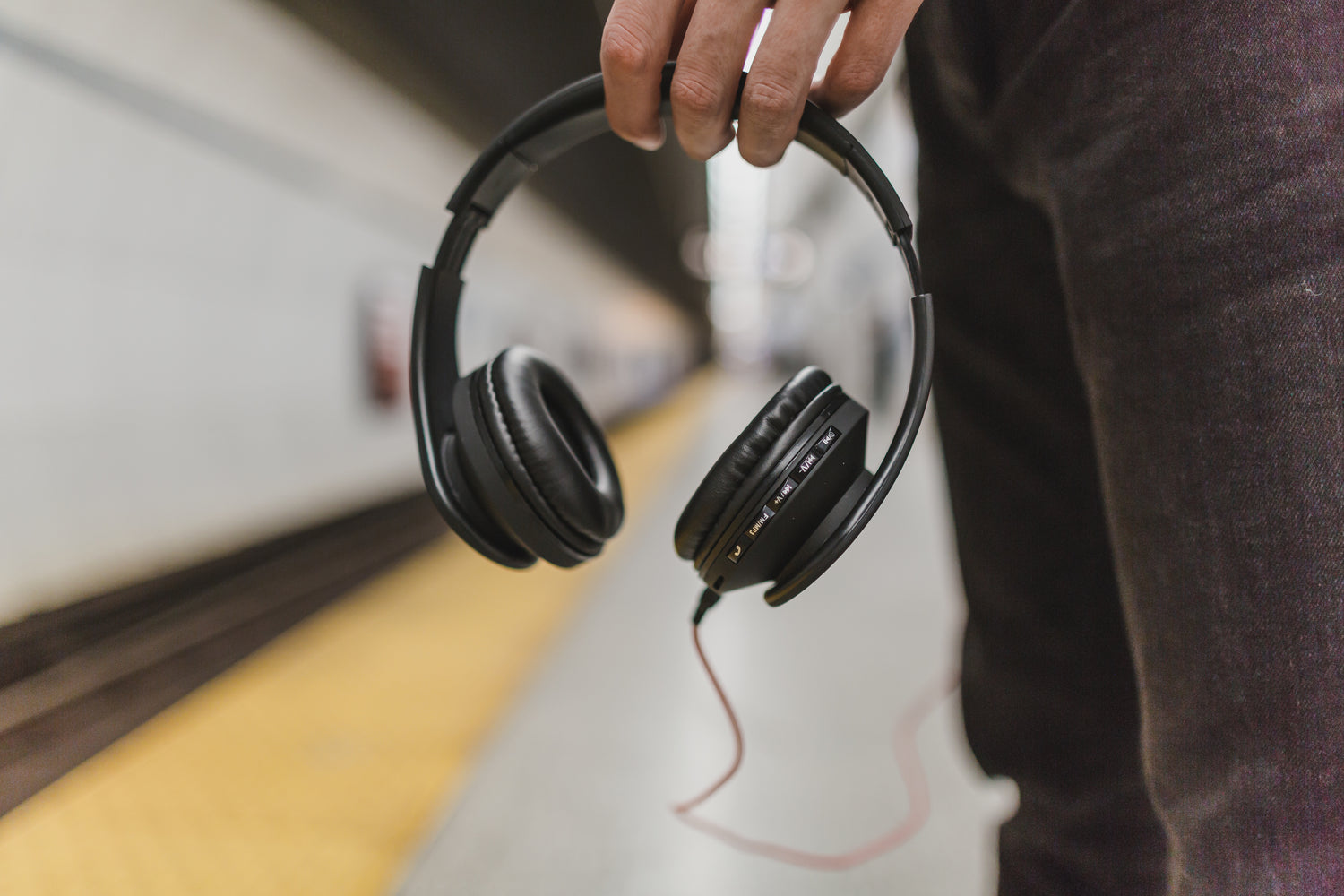 Man holding headphones in a train station